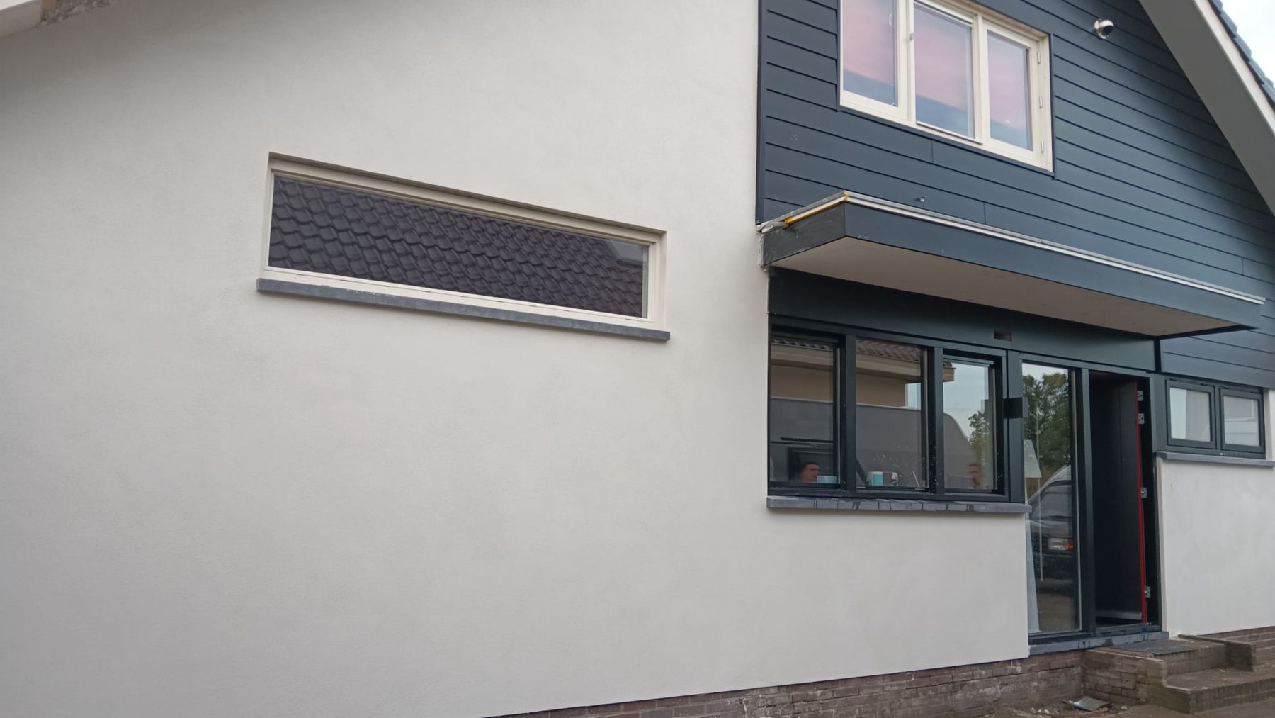 Close-up van de glad gestucte gevel onder donkere gevelbekleding