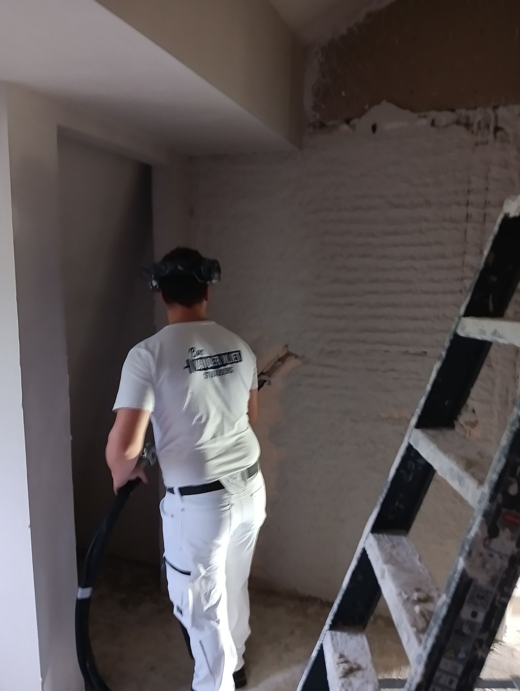 Stukadoor in witte werkkleding aan het werk op een binnenmuur